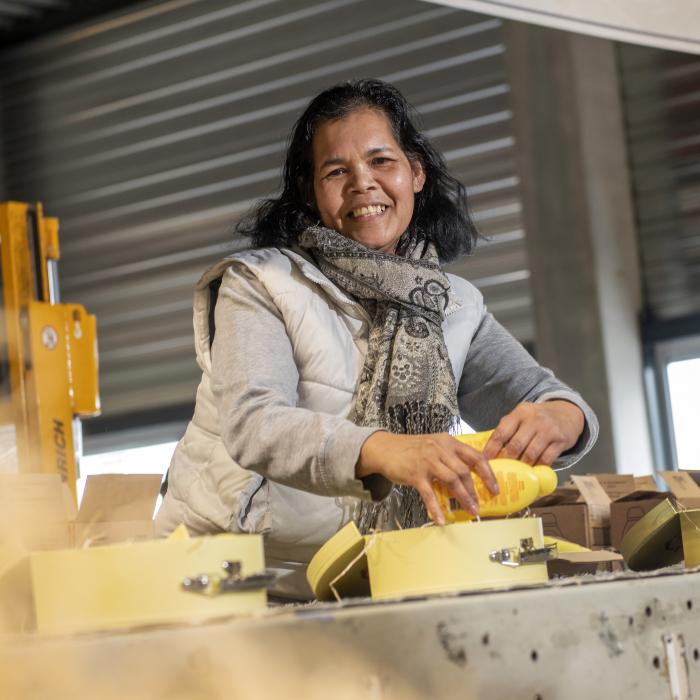 Afbeelding: vrouw aan werktafel pakt dozen in